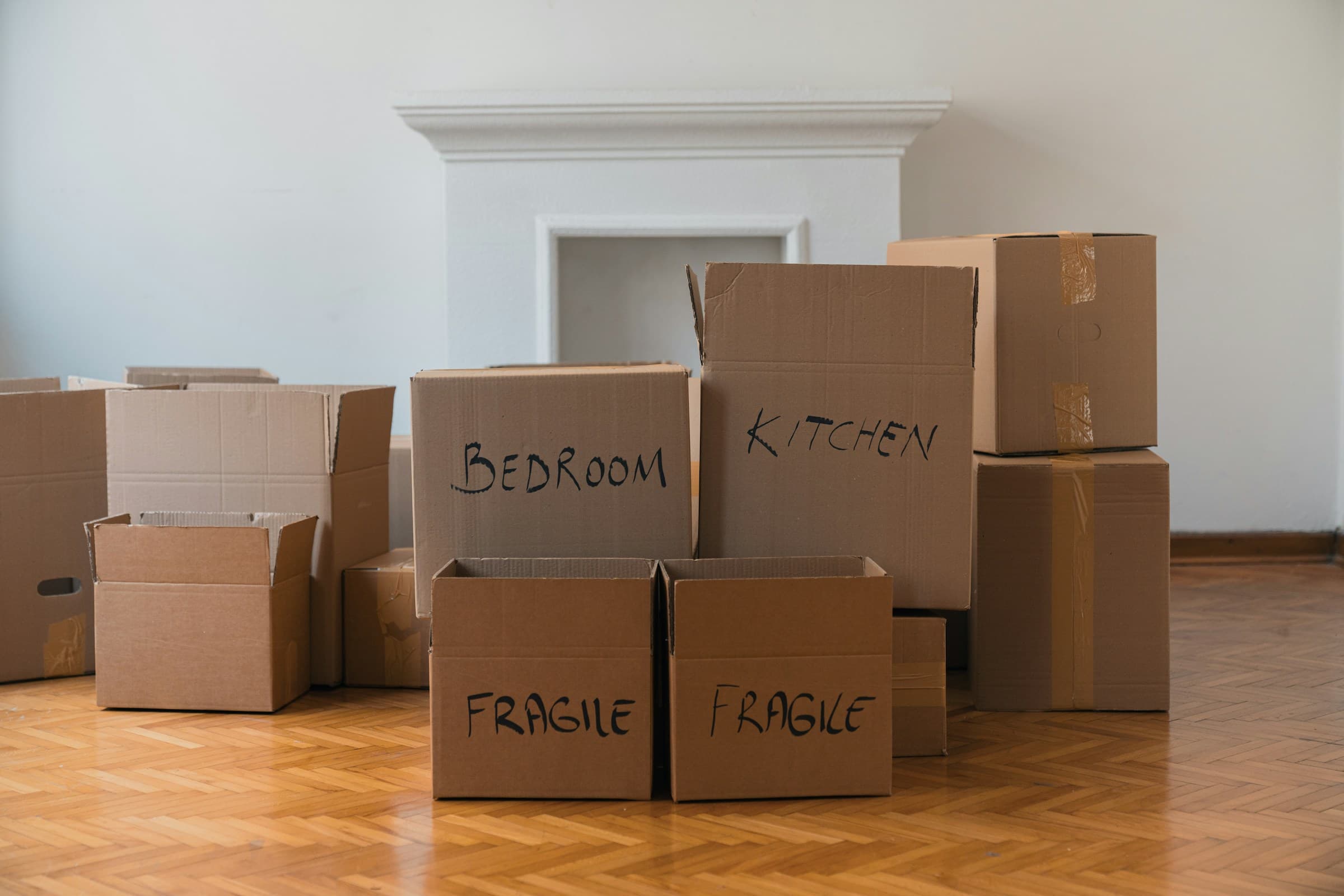 Some moving boxes on the floor, some have some hand written text on them